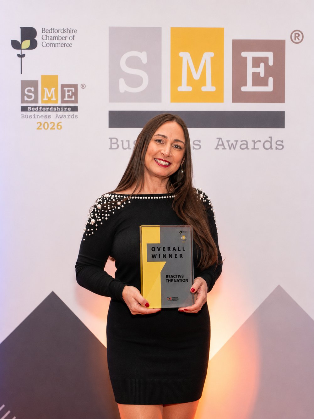 Michelle Crook holding the SME Bedfordshire Overall Winner award for Reactiv8 the Nation